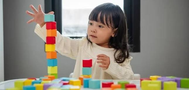 Anak sedang menyusun balok warna