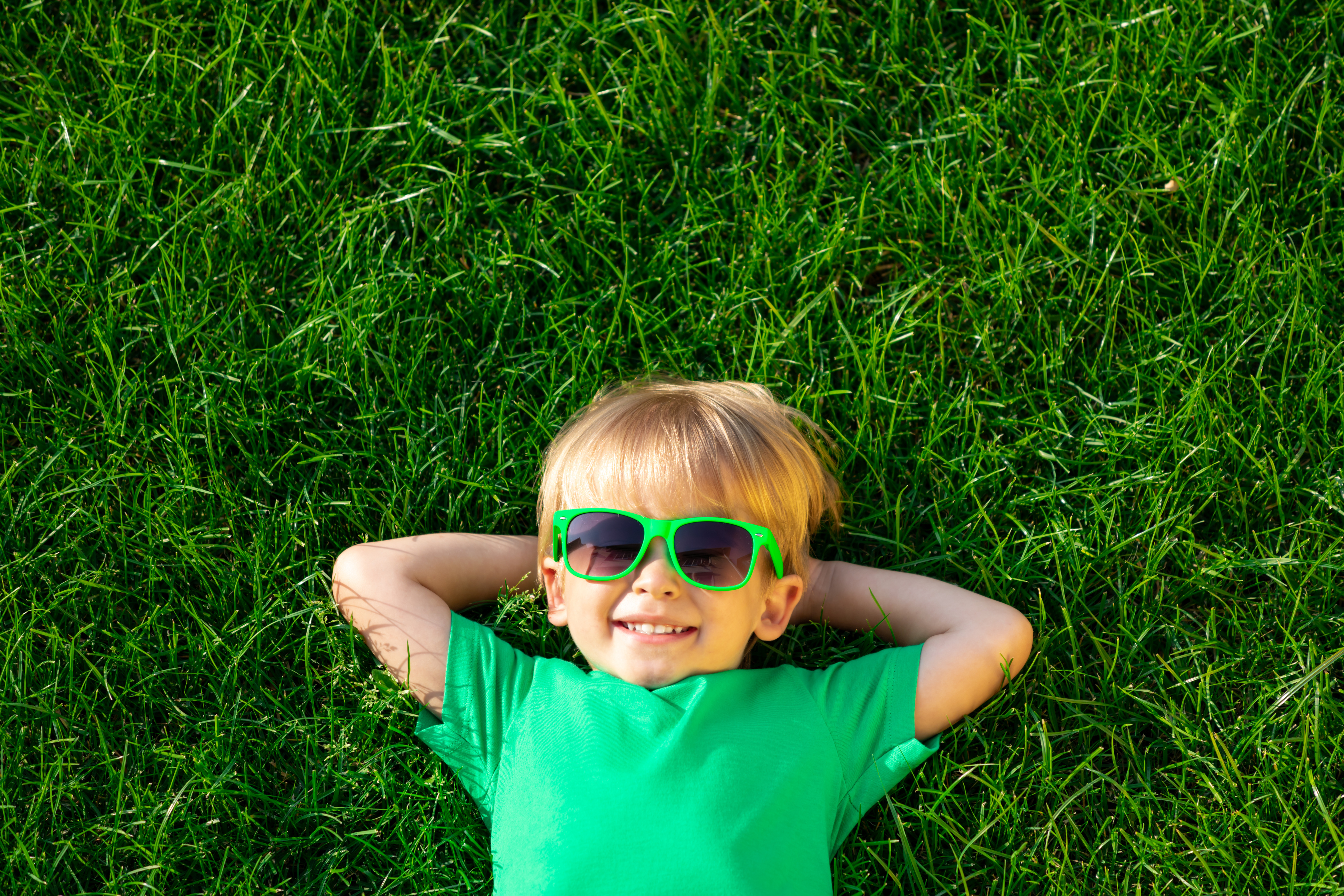 Happy Child Lying on Spring Green Grass